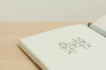 Drawing heart in tic tac toe on paper with pen,xo game,love concept.