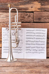 Trumpet and musical notes sheets. Old trumpet and musical notes on rustic wooden background....