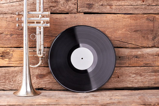 Trumpet and vinyl record on old wood. Vintage musical instruments on rustic wooden planks.