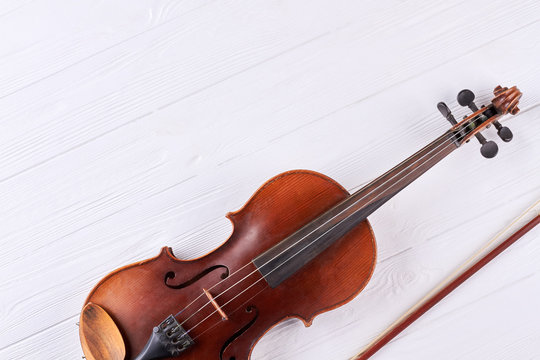 Violin with fiddle stick and copy space. Vintage violin from brown wood on white background. Musical instrument of orchestra.