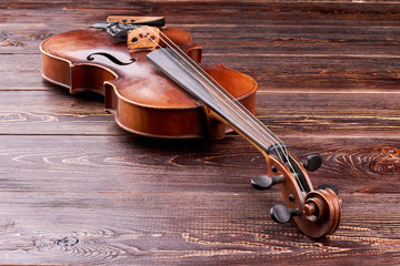Violin on brown wooden background. Stringed musical instrument and copy space. Antique equipment of...