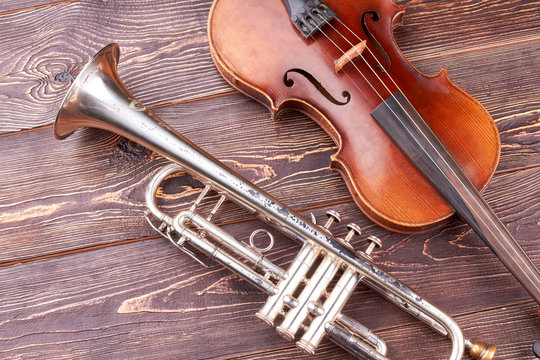 Vintage trumpet and cello on wooden background. Old-fashioned equipment of classical music.