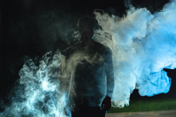 The man standing in the smoke on the dark background