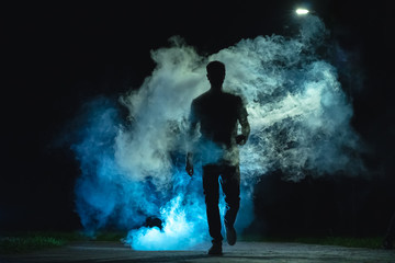 The man walking in the blue smoke on the dark background