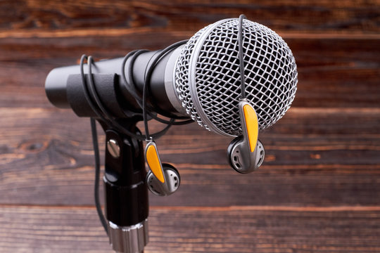 Close up microphone with earphones. Gray microphone and earphones on wooden background. Modern musical technologies.