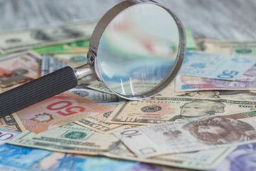 Currency and a magnifying glass, soft focus background