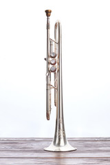 Trumpet instrument on wooden table. Silver trumpet over white background. Classical wind instrument.