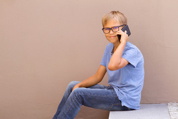 Kid talking on cell phone against colorful building wall outdoors