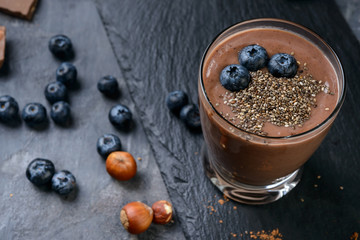 Chocolate smoothie with bluberry, nuts and chia seeds on a gey background