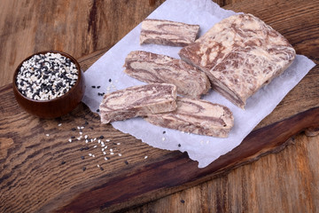 Halva with sesame seeds of two colours on a wooden board
