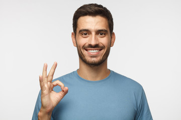 Young smiling man having happy look, gesturing, showing OK sign or showing okay gesture with his...