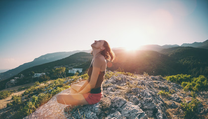 A girl is sitting on top of a mountain and smiling.