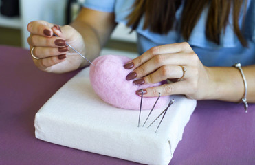 closeup young caucasian woman hands making wool dry felting tutorial. female showing needle felted toy master class. Hobby, handmade, crafting, leisure, teaching, education, creativity, design concept