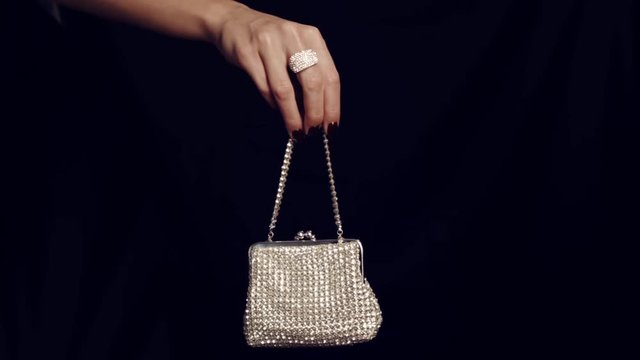 Woman hand holding vintage elegance-handbag decorated  with diamond isolated on black background. Handbag made of diamonds. Female sparkling glamour luxury silver diamond purse handbag.