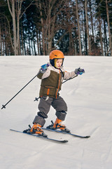 Fototapeta na wymiar Active young boy skiing in mountains and enjoying vacation