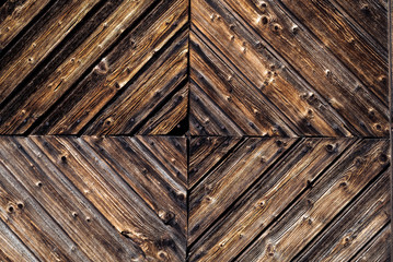 Closeup detail of a rustic, weathered wood wall with textured decorative woodwork
