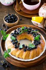 Delicious dessert black currant, sweet delicious holiday cake with black currant and lemon glaze on a table in a rustic style.