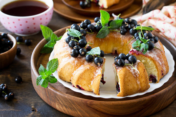 Delicious dessert black currant, sweet delicious holiday cake with black currant and lemon glaze on a table in a rustic style. Copy space.