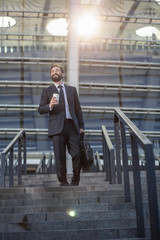 Cheerful smiling businessman walking down the stairs