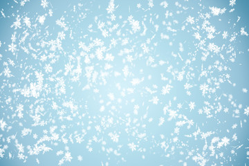 Snowfall in the winter sky. Falling snowflakes and a blue cold sky. Winter. New Year.