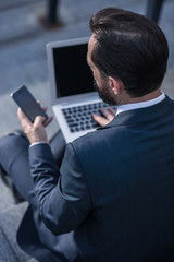 Rear view of a pleasant businessman using his phone