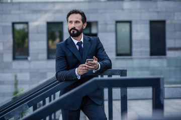 Confident bearded businessman leaning on the handrail