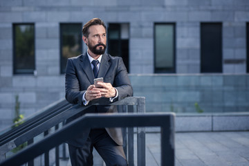 Serious handsome businessman leaning on a handrail