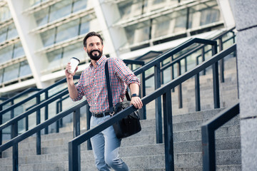 Cheerful handsome man drinking tasty coffee outdoors