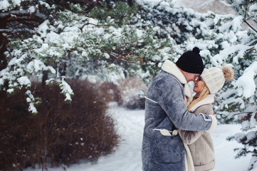 Fototapeta na wymiar winter portrait of romantic couple kissing in snowy forest. Valentine's day or holiday concept.