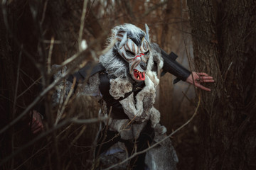 Threatening creature resembling a human wolf in the forest among the trees.