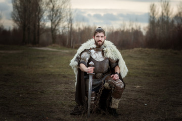 Knight in armor with a sword in hand, standing on one knee.