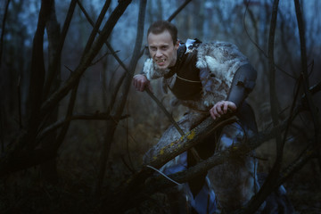 Werewolf with fangs at night in the forest among the trees.