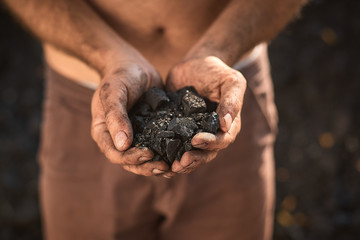 poor middle-aged man holding the hands of stone coal for sale