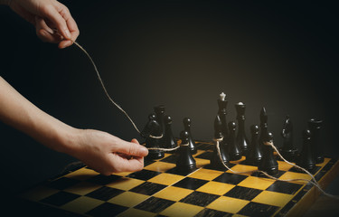 A chessboard with figures. The concept of manipulation is people. The hands pull the chess pieces....