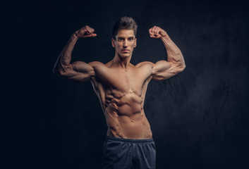 Fototapeta na wymiar Handsome shirtless man with stylish hair and muscular ectomorph shows his biceps.