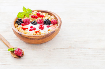 granola with berries on white wooden background