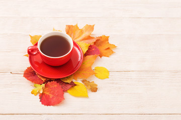 tea in red cup with autumn leaves on white table