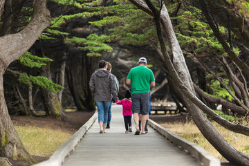 Fototapeta na wymiar Family walking on wooden boardwalk leading to the beach