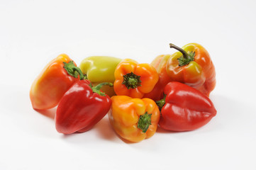 Multicolored sweet pepper on a white background. In a pile of pepper red, yellow, green, orange. Close-up.