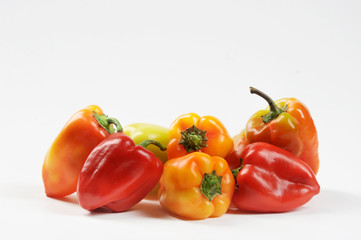Multicolored sweet pepper on a white background. In a pile of pepper red, yellow, green, orange. Close-up.