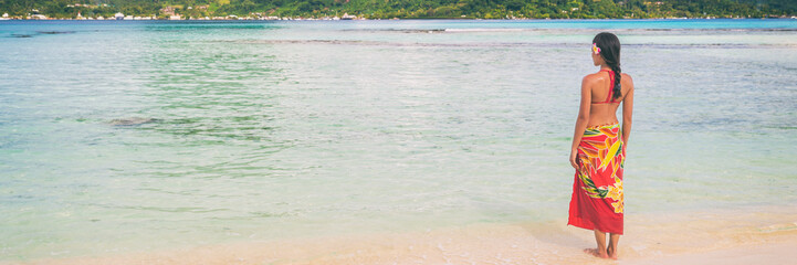 Beach summer polynesian skirt woman relaxing walking on sand and ocean background. Banner travel...