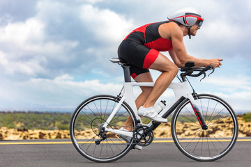 Fototapeta na wymiar Cycling sport athlete man biking on triathlon bike. Fit male cyclist on professional triathlon bicycle wearing time trial helmet for ironman race. Exercising in Kailua Kona, Big Island, Hawaii, USA.