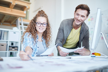 Obraz premium One of young specialists pointing at paper while explaining her colleague financial data at meeting