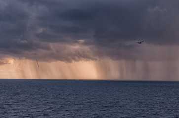 dense rain clouds and a tornado over the sea