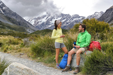 Hikers people eating lunch taking a break during hike on mountain hiking adventure. Tourists relaxing on Hooker Valley track towards Mt Cook on summer travel in New Zealand.