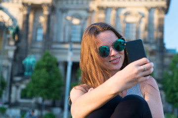 girl make selfie photo on smartphone in germany near berlin cathedral. modern life girl with...