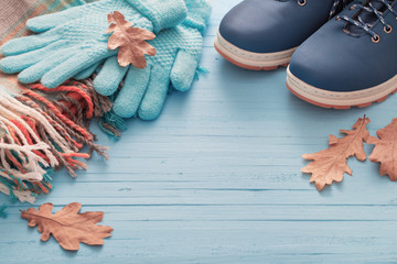 Fototapeta na wymiar blue winter shoes and gloves on blue wooden background