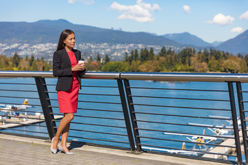 Vancouver city Asian canadian woman drinking coffee at harbor view during office break in the morning. Professional businesswoman thinking outside in the sun.