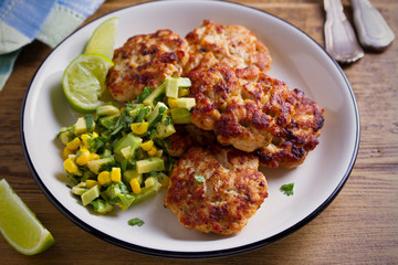 Homemade chicken patties or burgers with avocado corn salsa. horizontal