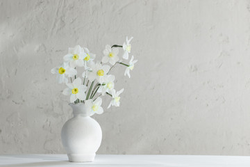 white narcissus in vase on wooden table